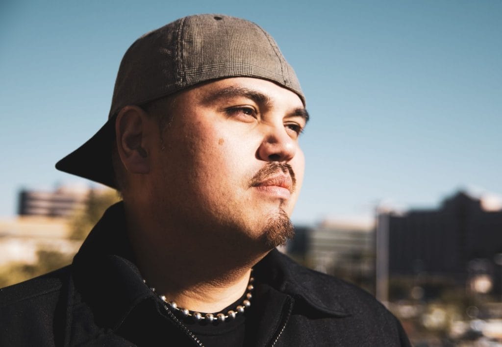 Young Latino man wearing a hat backwards. 